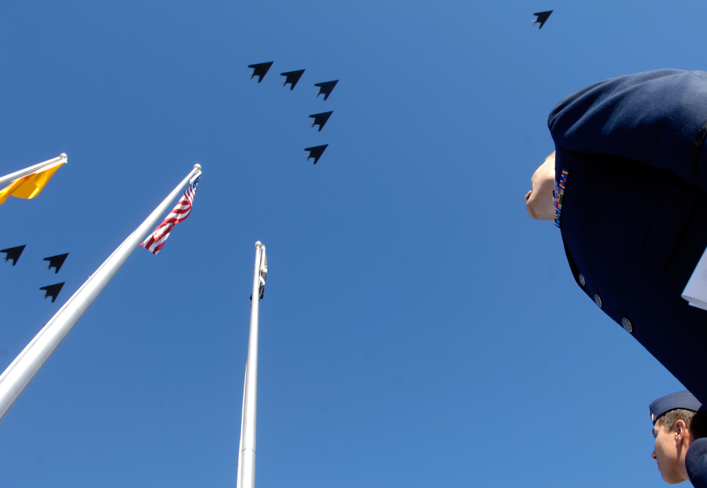 A flight of F-117 jets zoom overhead during a ceremony. (Air Force)